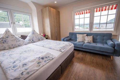 a bedroom with a bed and a blue couch at Das Gästehaus in Valwig in Valwig