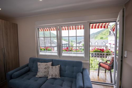a blue couch in a living room with windows at Das Gästehaus in Valwig in Valwig