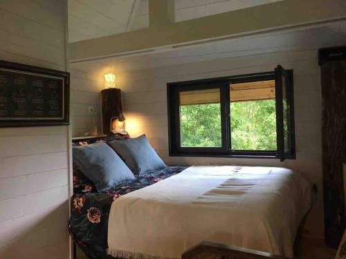 une chambre avec un grand lit et une fenêtre dans l'établissement Les Grands Bois Gite et cabane, à Thézac
