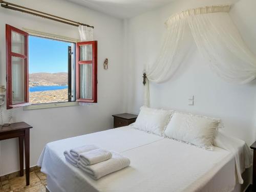 a white bedroom with a bed with towels on it at Niriides Studios & Apartments in Kithnos