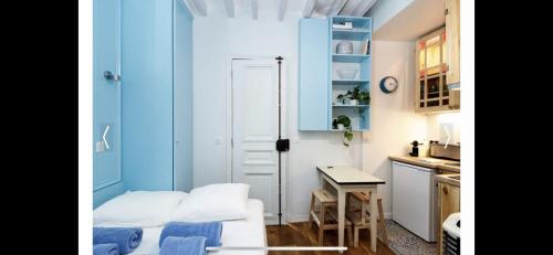 une petite cuisine avec des murs bleus et une table dans une pièce dans l'établissement PARIS 4 Le Marais Place des Vosges, à Paris