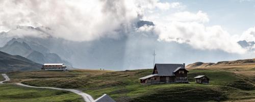 a house on the side of a hill with a road at Berghotel Distelboden in Frutt