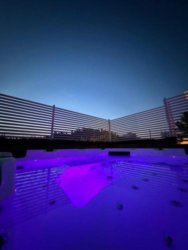 a swimming pool with purple lights in front of a bridge at Hotel Adria B&B - Colazione fino alle 12 in Misano Adriatico