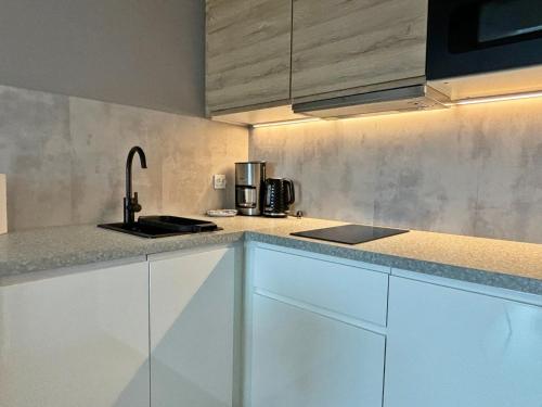 a kitchen with white cabinets and a sink at Sun Towers - Apartamenty Bryza - Apartamenty z parkingiem in Świnoujście
