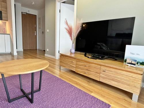 a living room with a large television and a table at Sun Towers - Apartamenty Bryza - Apartamenty z parkingiem in Świnoujście