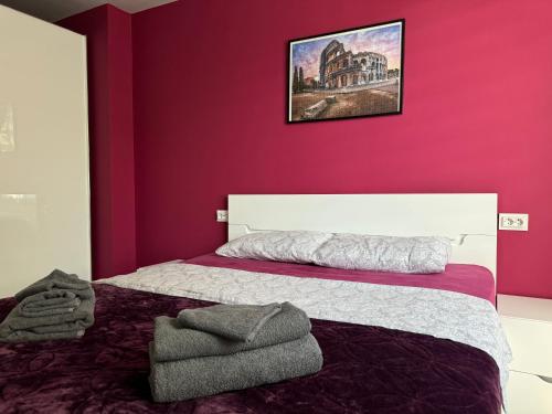 a bedroom with a red wall with a bed and a picture at West Park Apartment in Sofia