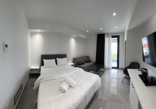 a white bedroom with a large bed and a living room at Eleva Deluxe in Kastoria