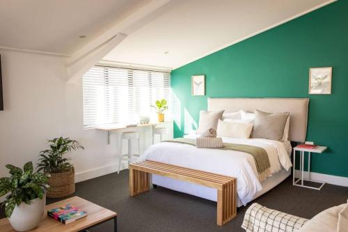 a bedroom with a large bed and a green wall at Ocean-View Studio Apartment, Hermanus Waterfront - Apt 8 in Hermanus