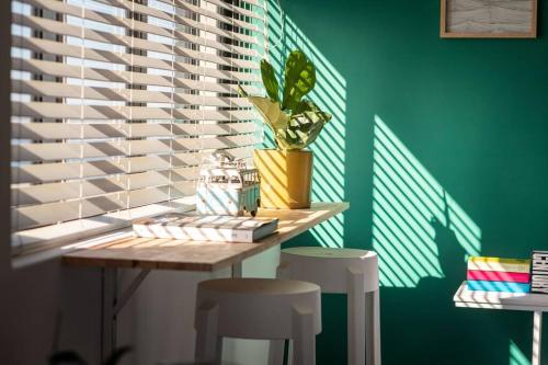 a table with stools and a plant on a green wall at Ocean-View Studio Apartment, Hermanus Waterfront - Apt 8 in Hermanus