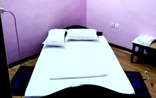 a bedroom with a white bed with a purple wall at Homestay in Baglung Bazar -Baglung Homestay in Bāglung