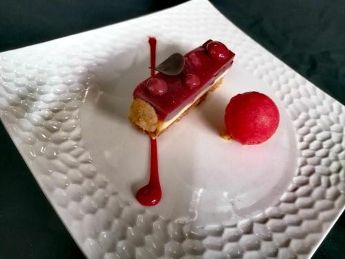 a piece of dessert on a white plate with a cherry at Logis Hotel Schaeffer- Restaurant Le Saint Georges in Serrières