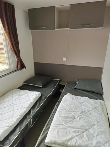 deux lits dans une chambre avec une fenêtre dans l'établissement Mobil-home INTUITION 8P, à Saint-Jean-de-Monts