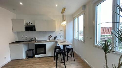 une cuisine avec des armoires blanches et des tabourets de bar dans l'établissement Climatisation, Ascenseur R5 Sublime T2 tout neuf, à Toulouse