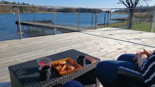 a person sitting on a deck with a tray of food at Villa Solsa in Nynäshamn