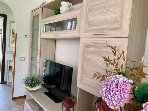 a living room with a tv and a cabinet with flowers at Casa dell’Artista in Luino