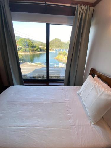 a bedroom with a bed and a large window at Casa da Mila in Rio Caldo