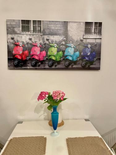 a table with a vase and a painting of scooters at Gästehaus Vigliarolo gewerblich Jedes Zimmer eigenes Bad Gemeinschaftsküche in Elmshorn