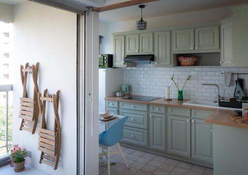 una cocina con armarios blancos y una silla azul en Le coquet à 20min de Paris et de l'aéroport d'Orly, en Juvisy-sur-Orge