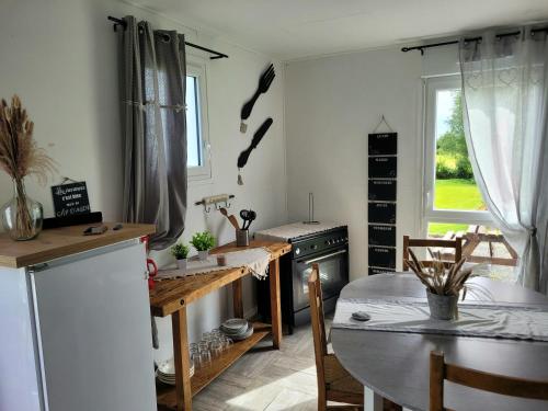 une cuisine avec une table et une salle à manger dans l'établissement Au bord de l'eau, à La Neuville-aux-Tourneurs