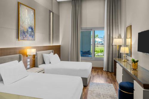 a hotel room with two beds and a television at Gewan Palace New Alamein in El Alamein