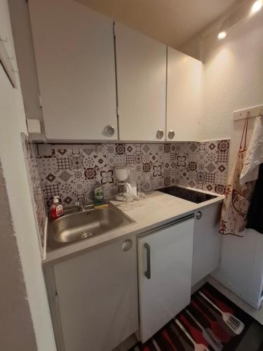 Elle comprend une petite cuisine avec un évier et des placards blancs. dans l'établissement Mongie Appart, à Bagnères-de-Bigorre