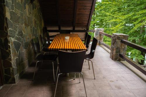 a wooden table and chairs on a balcony at Pensiunea Lac in Arefu