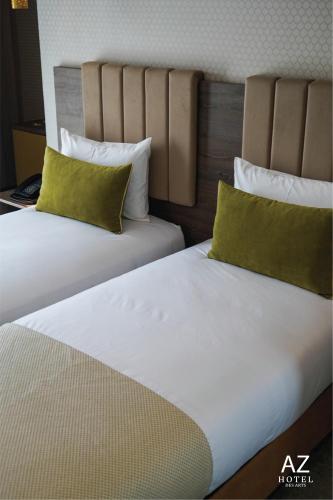 two beds with green pillows in a hotel room at AZ hôtel des arts in Rabat