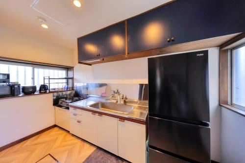 a kitchen with a black refrigerator and a sink at 慶村 歌舞伎 in Fujikawaguchiko