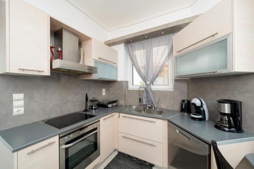 a kitchen with white cabinets and a sink at Apollonian villa in Artemida