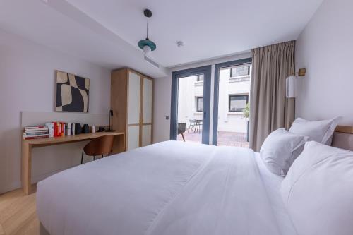 a bedroom with a large white bed and a desk at Quartier Libre Opera in Paris