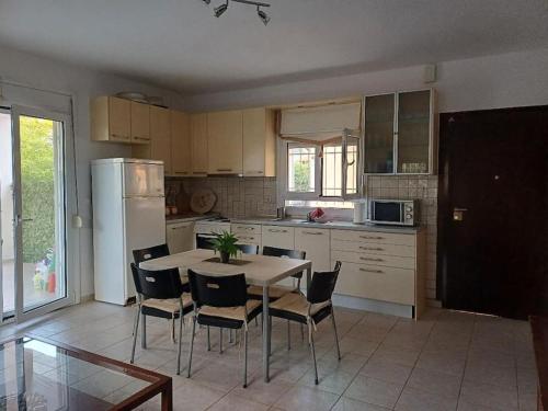 Una cocina con mesa y sillas y un refrigerador. en George house, en Paliouri