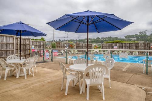 a group of tables and chairs with blue umbrellas at Sand and Sky in Bayshore