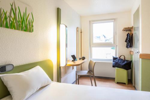 a bedroom with a bed and a desk and a window at ibis budget Compiègne Centre-Ville in Compiègne