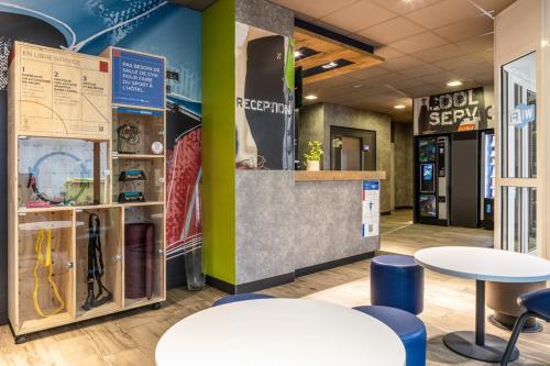 a lobby with two tables andools in a store at ibis budget Compiègne Centre-Ville in Compiègne