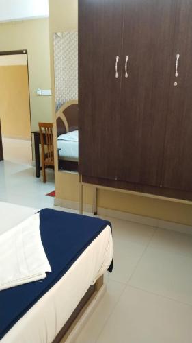 a bedroom with a bed and a wooden cabinet at Hotel Falcon in Trivandrum
