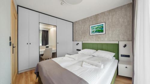 a bedroom with a white bed with a green headboard at Apartamenty Helski Brzeg in Hel