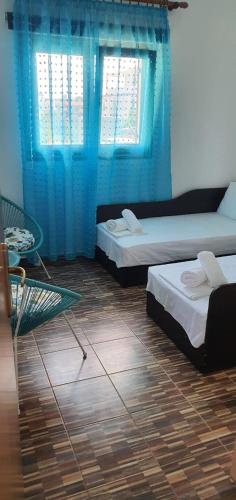 two beds in a room with blue curtains at Maria’s Sunset House in Megalochori