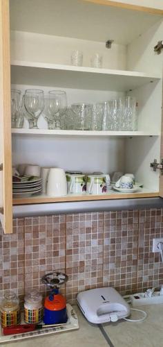 a kitchen shelf with glasses and dishes on it at Maria’s Sunset House in Megalochori