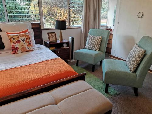 1 dormitorio con 1 cama de color naranja y 2 sillas en Hodson Villa, en Harare
