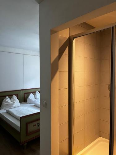 a room with a bed and a shower with a mirror at Gasthof Sterzingerhof in Vipiteno