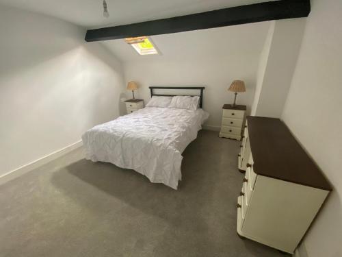 a bedroom with a bed and a dresser and a sink at Brithdir Cottage in Merthyr Tydfil