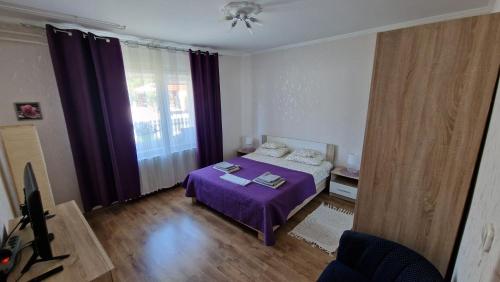 um quarto com uma cama roxa e uma janela em Inna Apartman em Hévíz