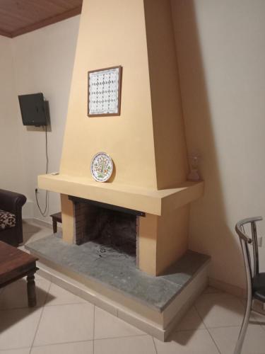 a living room with a fireplace with a clock on it at Guesthouse Kallisti in Anilio Pelion