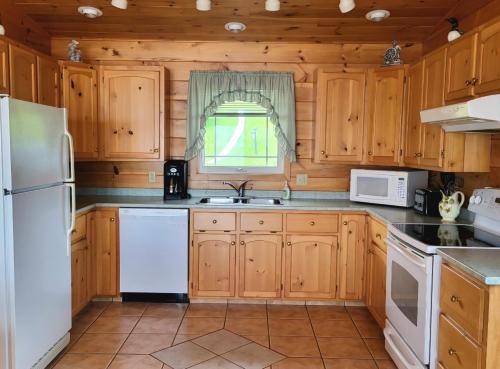 une cuisine avec des armoires en bois et un réfrigérateur blanc dans l'établissement True Living Oceanfront Cottage, à Cumberland