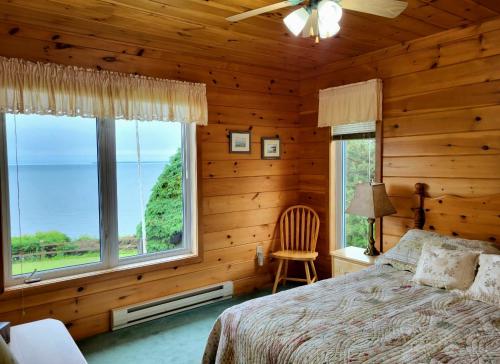 - une chambre avec des murs en bois, un lit et une fenêtre dans l'établissement True Living Oceanfront Cottage, à Cumberland