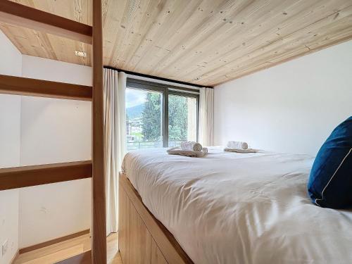 un grand lit dans une chambre avec une fenêtre dans l'établissement Cedrela-appartement-5-7pers-Centre station, aux Gets