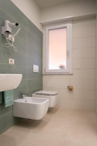 a bathroom with a toilet and a sink and a window at Pasitea Tropea in Tropea