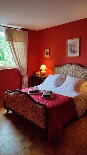 - une chambre dotée d'un lit avec un mur rouge dans l'établissement Chambre d'Hôtes La Closerie, à Tourneville