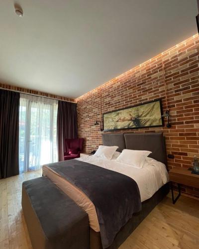 a bedroom with a large bed with a brick wall at Rozafa Fish City Hotel in Labinot i Poshtëm