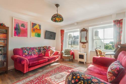 a living room with a red couch and chairs at Alnwick Book Nook - dog friendly in Alnwick